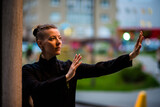 Fototapeta Miasto - Asian woman trains tai chi in the city, chinese martial arts, healthy lifestyle concept.