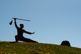 Fototapeta Miasto - Asian woman with sword practicing taijiquan at sunset, chinese martial arts, healthy lifestyle concept.