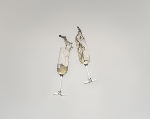 Splash of two crystal glasses toasting with champagne for a celebration. Splash on white cut-out background.