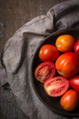 Wall Mural - heap of tomatoes on a plate, freshly harvested red berries on a wooden surface, taken from above