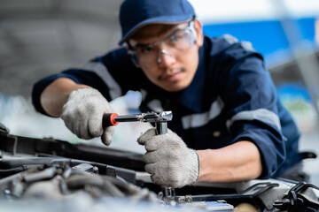 Wall Mural - Portrait of an Asian mechanic with repair equipment standing confidently in a car repair shop. Auto mechanic in the service center. Car safety inspection. Repair service concept. hand focus