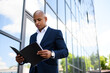 © Dmytro Hai - African american businessman in suit looking at documents on urban street