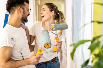 Young couple painting wall in their home.