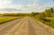 Empty Sandy country road near the forest,fluffy clouds blue sky,summer evening landscape.