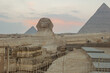 Landscape with Egyptian pyramids, Great Sphinx and silhouettes Ancient symbols and landmarks of Egypt for your travel concep in golden sunlight. The Sphinx in Giza pyramid complex at sunset
