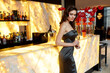 © Dragosh - Profile of a sensual young woman dressed in grey dress and makeup, posing at the bar with glass.