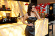 © Dragosh - Profile of a sensual young woman dressed in grey dress and makeup, posing at the bar with glass.