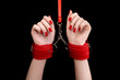 © Granmedia - BDSM outfit for adult sex games. Close-up of female hands with red manicure chained with red handcuffs