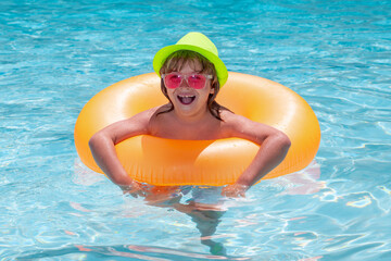 Wall Mural - Kid boy playing with inflatable floating ring in swimming pool. Summer vacation concept. Summer kids portrait in sea water on beach.