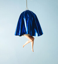 Bird Cage Covered With Blue Fabric, Doll's Legs Exposed. Creative Concept, Pastel Blue Background.