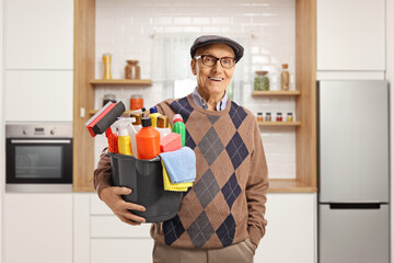 Sticker - Elderly man holding a bucket with cleaning supplies and standing in a kitchen