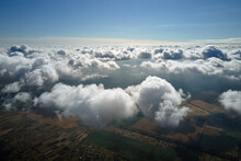 Aerial View From Airplane Window At High Altitude Of Earth Covered With White Puffy Cumulus Clouds