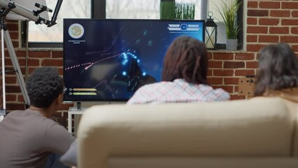 Wall Mural - Young people playing video games challenge on cyberspace, using console in living room. Friends feeling happy and having fun with online action gameplay competition for entertainment.