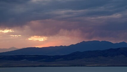 Wall Mural - Sunset timelapse as rainstorm moves over the mountains looking past Utah Lake during summer monsoon.