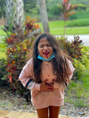 young girl in pain holding stomach with bloody nose dripping on shirt 