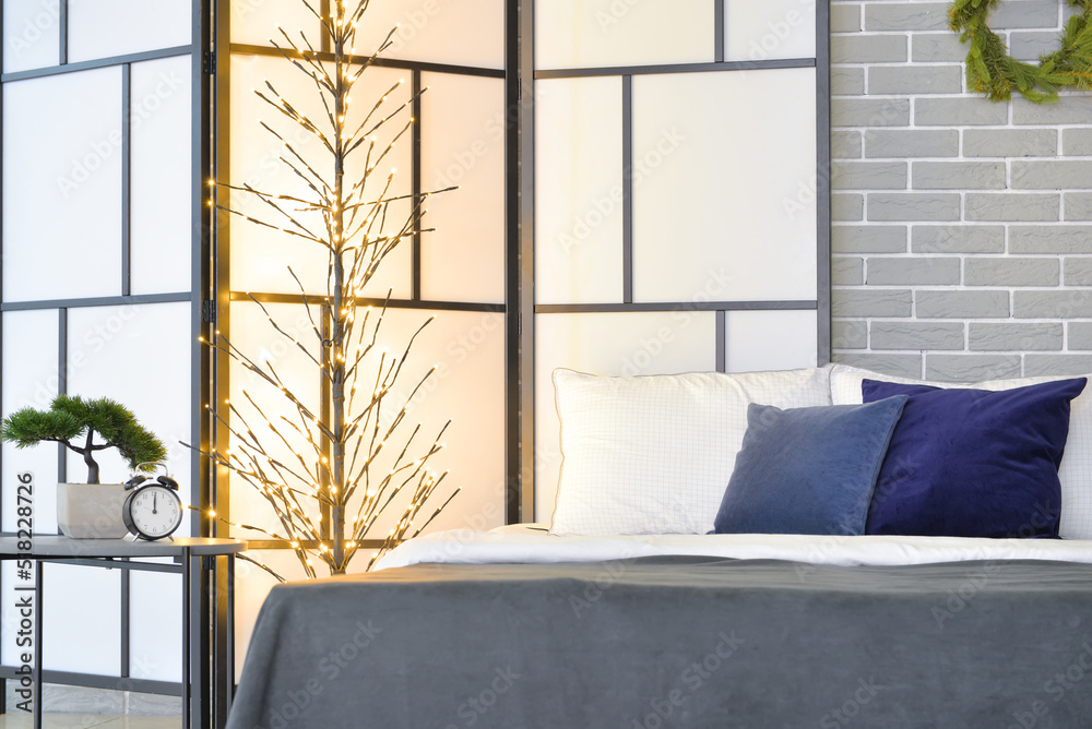 Interior of stylish bedroom with folding screen and glowing lights
