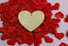 A Heart Carved From Wood Lies On A Pile Of Red Hearts Made Of Cloth. Romantic Greeting Card