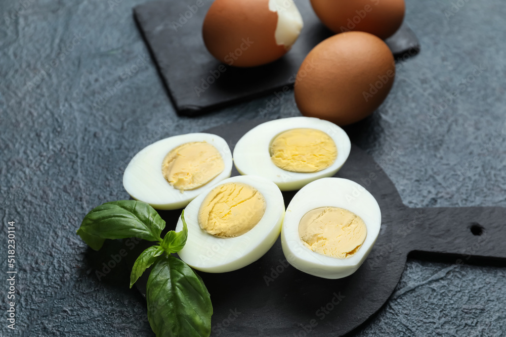 Board with halves of boiled chicken eggs on dark background, closeup