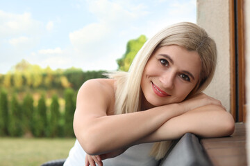 Sticker - Portrait of beautiful woman sitting near house in yard, space for text