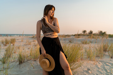 Wall Mural - Sexy  brunette woman in stylish summer  boho outfit posing on the beach.  Sunset colors.