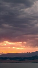 Wall Mural - Timelapse of sunset glowing behind dark clouds as storm moves in.