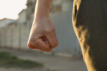 Angry man with clenched fist outdoors, closeup