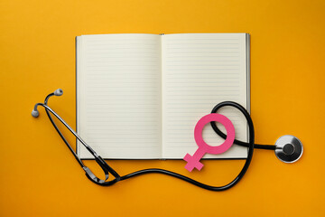 Wall Mural - Female gender sign, open notebook and stethoscope on orange background, flat lay. Women's health concept