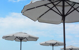 Fototapeta Tęcza - Beautiful white beach umbrellas against blue sky