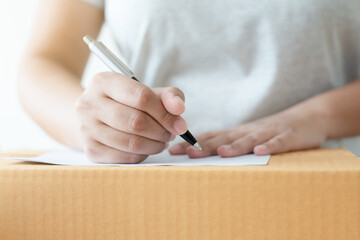 Wall Mural - Woman business owner writing down customer address to deliver parcel. Preparing to delivery write down address before shipment.