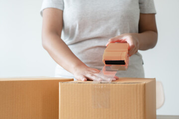 Wall Mural - Woman sealing tape cardboard box preparing to delivery. Parcel in packing process to shipping service. Household business during pandemic.