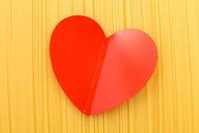 spaghetti yellow background with a red heart close. raw pasta macro