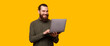 © Vulp - A happy bearded man is typing in his laptop near a free and yellow copy space