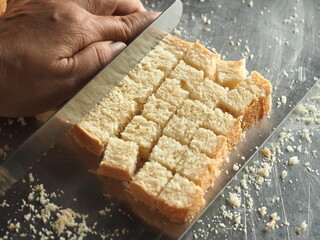 slicing white bread into cubes for making croutons