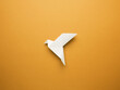 Origami peace dove on an orange paper background, freedom or peace concept