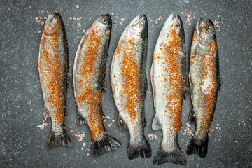 Seafood. Two raw rainbow trouts marinated with lime, pepper, spices on a dark background. banner, menu, recipe place for text, top view