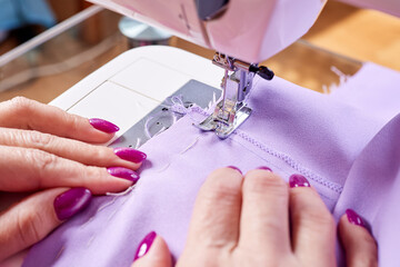 Wall Mural - Woman sewing a dress on a sewing machine. Close-up, selective focus