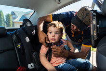 Father Buckling Child Into Car Seat Restraint