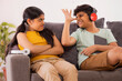 Young brother teasing his sister while sitting on sofa with digital tabletin living room