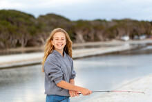 Smiling Happy Girl On Beach In Front Of Water With Fishing Rod
