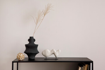 The stylish composition of minimalistic interior with copy space. White vase with dried flowers, sculpture and stylish accessories. Beige wall. Home decor. Template.