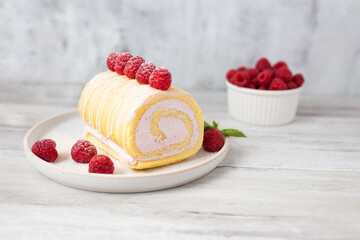 Tasty roll cake, sponge roll, Swiss roll  stuffed with cream cheese ,decorated with fresh raspberries.  