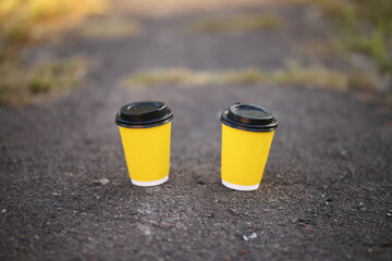 two yellow paper cups of coffee on a dark background