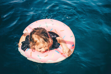 Wall Mural - Baby girl swimming with Inflatable ring in the sea.