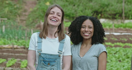 portrait of two diverse women standing at community farm. young people at communitarian organic urba