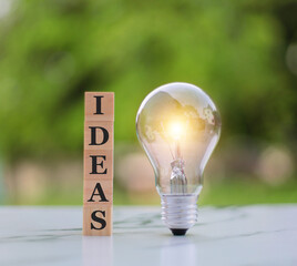 Wall Mural - idea and new creative thinking concept, light bulb with idea word on wood block on green background