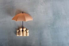 Umbrella and wooden dolls with copy space. Family protection and insurance coverage concept.