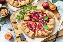 Plum Galette. Healthy homemade wholegrain fruit pie (galette) with plums and almonds, vegan vegetarian dessert on a stone table.