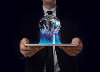 Wall Mural - internet technology concept. man holding tablet and virtual icon of earth on dark background
