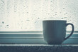 Cup of autumn tea, coffee or chocolate over rain drop window background, copy space. Hot drink for autumn cold rainy days. Hygge concept, autumn mood. Soft focus, toned