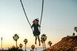 © Erin Brant/Stocksy - Happy girl on swing at sunset